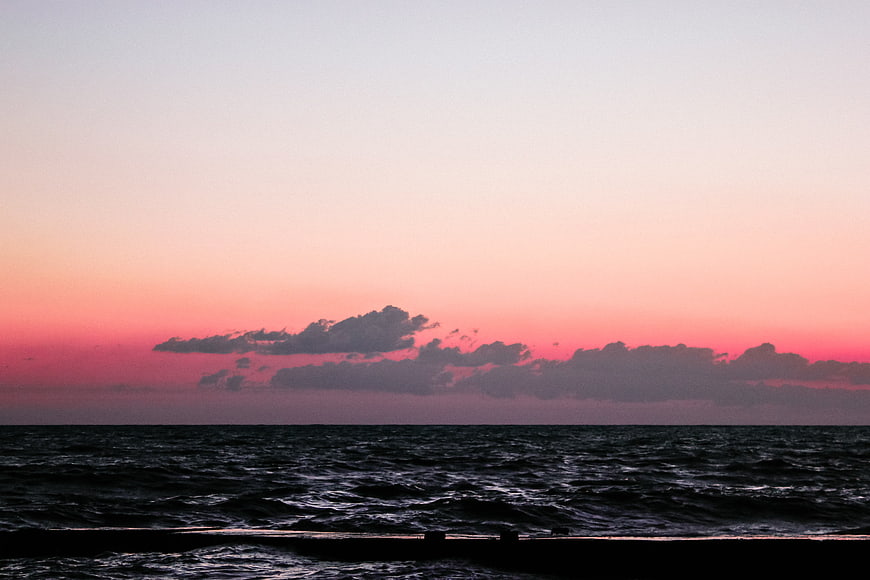 Dramatic Pink Sunset Over Dark Ocean Waves