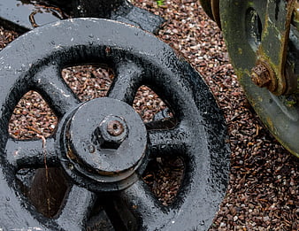 Close-up of wet black cast iron industrial wheel on gravel
