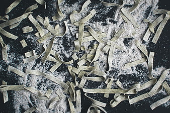 Fresh handmade pasta tagliatelle with flour on black background
