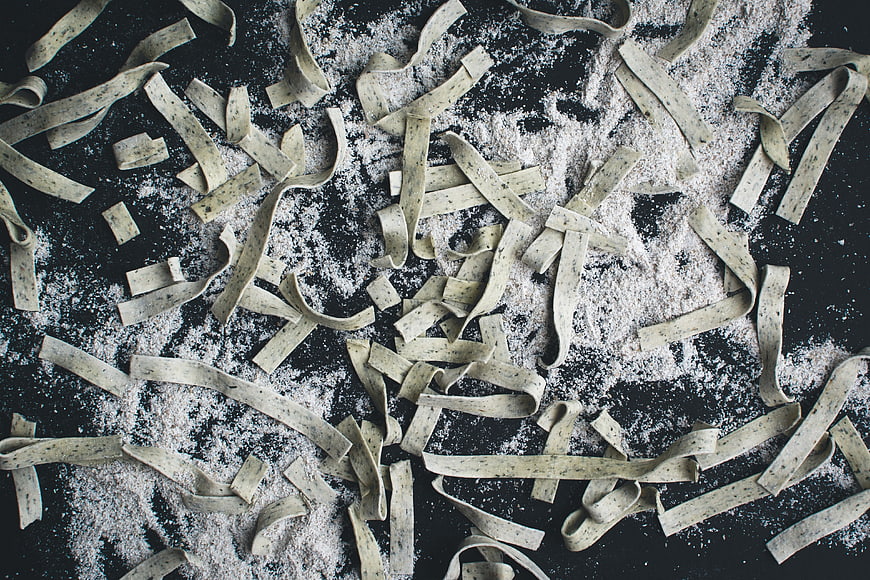 Fresh handmade pasta tagliatelle with flour on black background