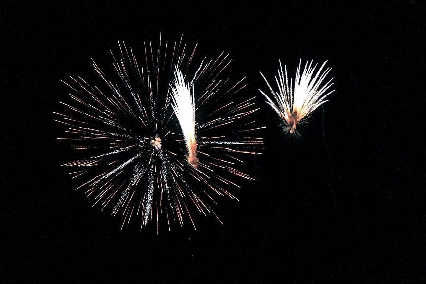 Fireworks exploding in the night sky with sparks