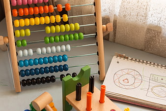 Colorful wooden abacus and children's drawing notebook on desk