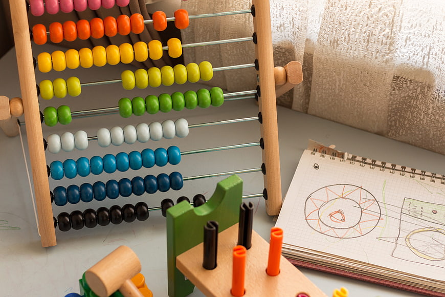Colorful wooden abacus and children's drawing notebook on desk
