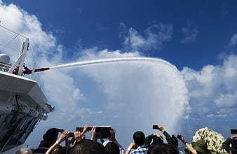 Water cannon spray from ship deck with crowd filming
