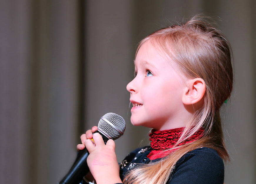 Young Girl Singing into Microphone in Profile