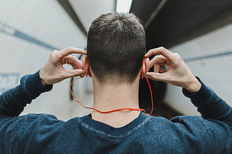 Man putting on orange headphones in tunnel