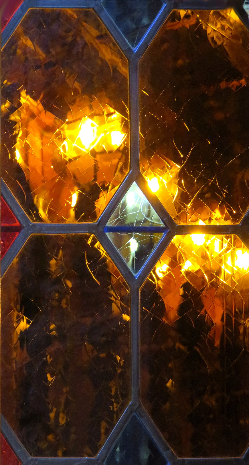 Close-up of amber stained glass window with geometric lead lines