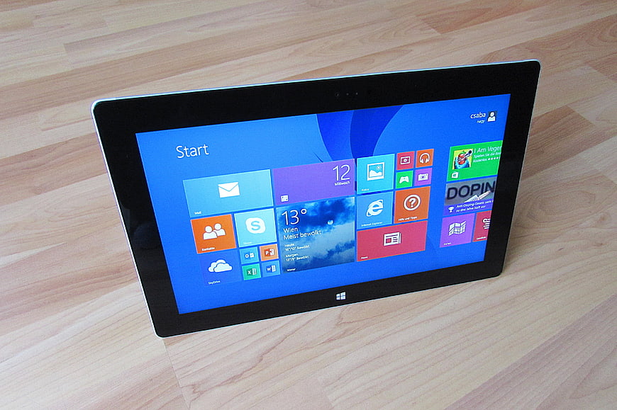 Microsoft Surface Tablet Displaying Windows 8 Start Screen on Wooden Surface