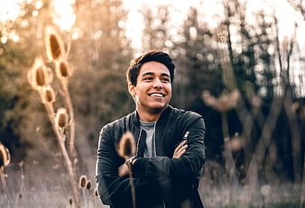 Happy young man smiling in field with bokeh background