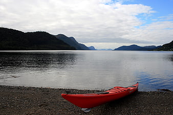 Red Kayak on Pebble Beach with Mountain Fjord View