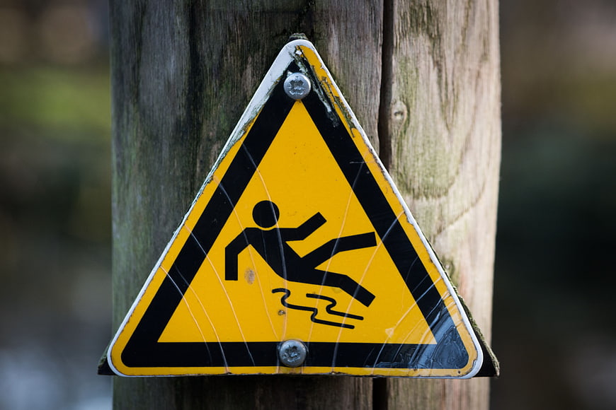 Yellow Slippery When Wet Warning Sign on Wooden Post