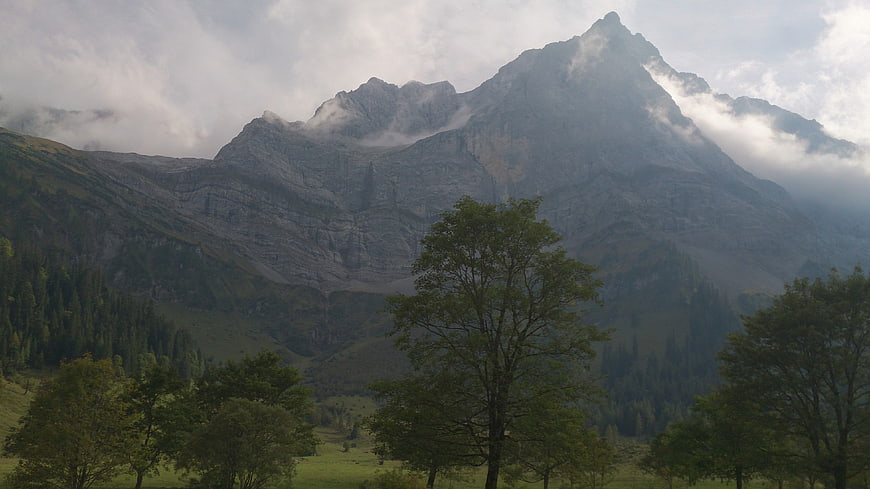 Majestic mountain peak with clouds and green trees