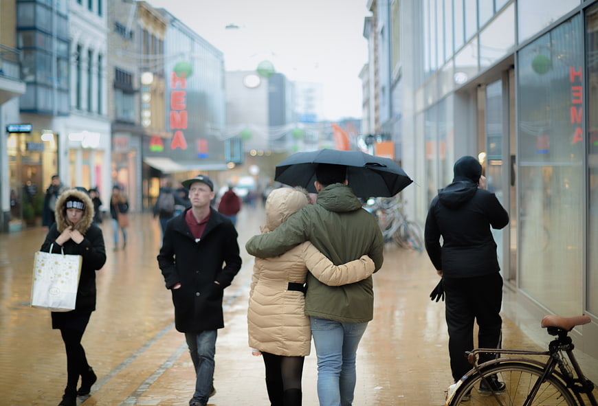 Couple walking under umbrella on rainy city street