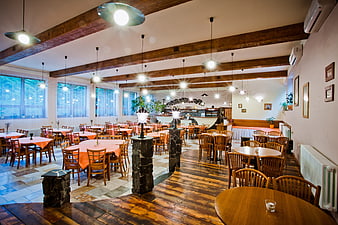 Spacious rustic restaurant interior with wooden beams and tables
