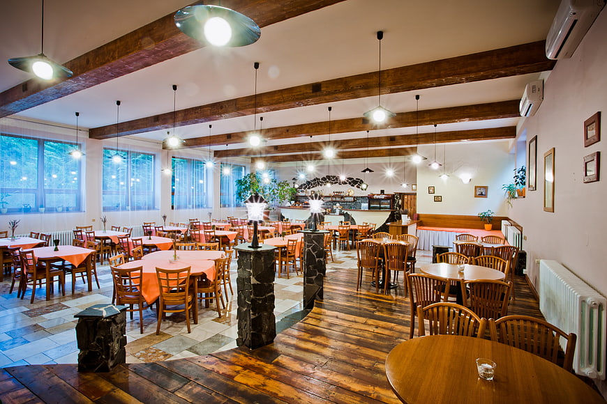 Spacious rustic restaurant interior with wooden beams and tables