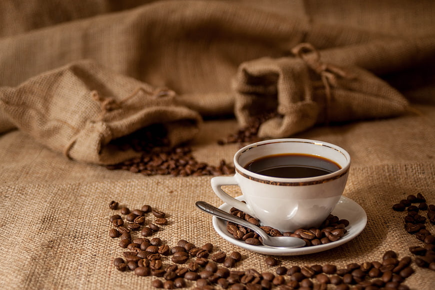 White Cup of Black Coffee with Beans on Rustic Burlap