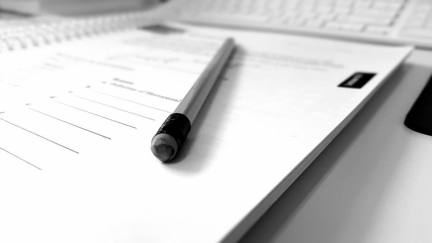 Pencil on worksheet with laptop keyboard in black and white