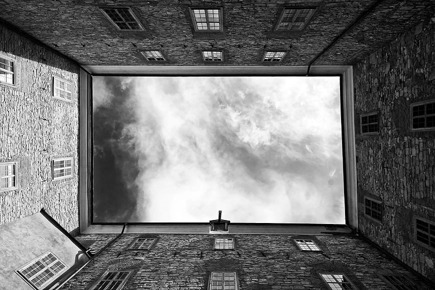 Black and white low angle view of stone buildings and cloudy sky