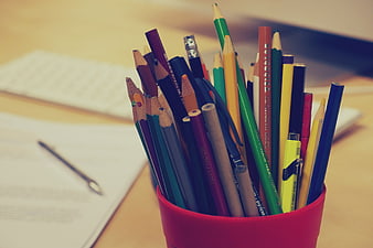 Colorful pencils in red cup on office desk