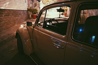 Vintage beige car parked in narrow alley at night