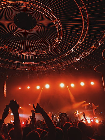 Energetic rock concert crowd with red stage lighting and truss