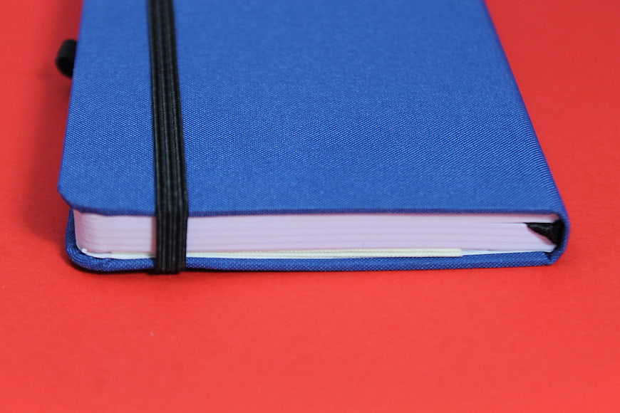 Blue Notebook on Red Background with Black Elastic Band