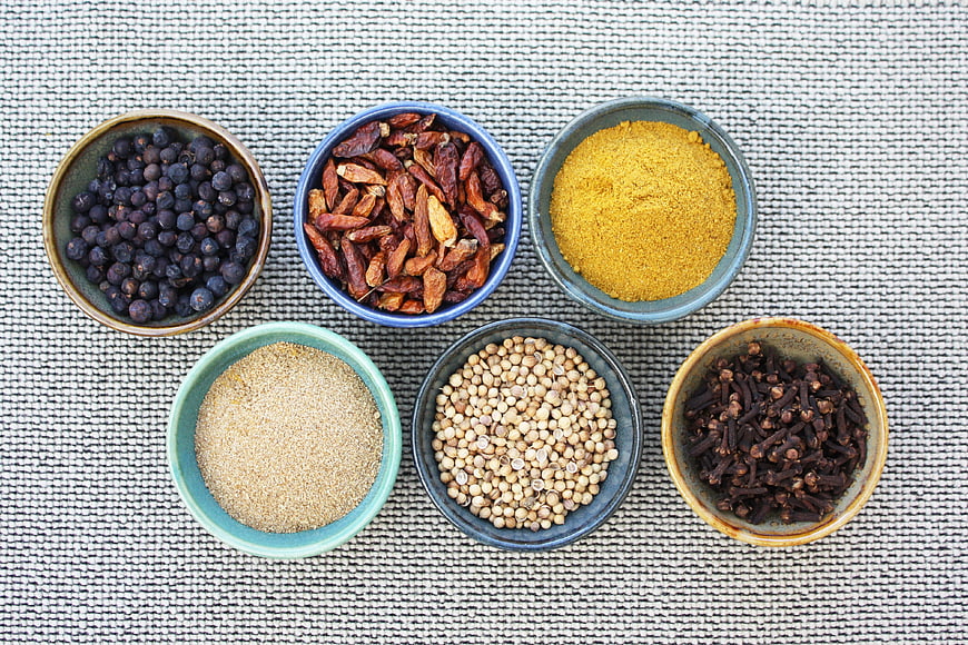 Top View of Assorted Spices in Ceramic Bowls on Textured Mat