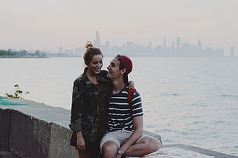 Young couple smiling together on waterfront with city skyline background