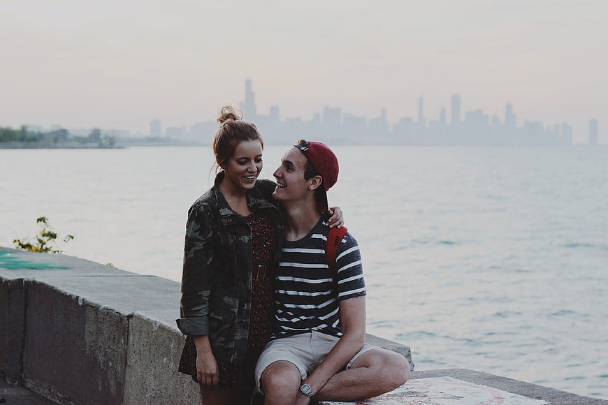 Young couple smiling together on waterfront with city skyline background