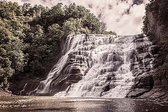 Wide cascading waterfall flowing over layered rocks in forest