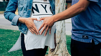 Pregnant Couple Making Heart Shape with Hands on Belly