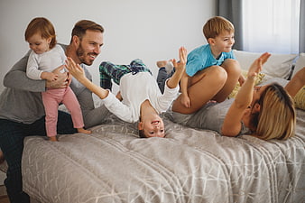 Happy family playing together on bed in bedroom