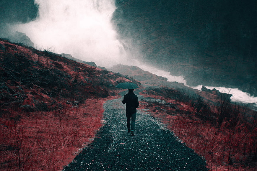 Lone figure with umbrella on misty mountain path