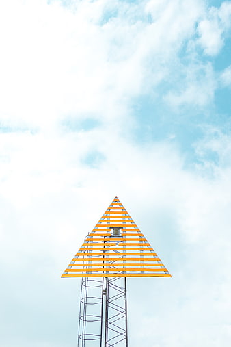 Yellow triangular tower structure against blue sky