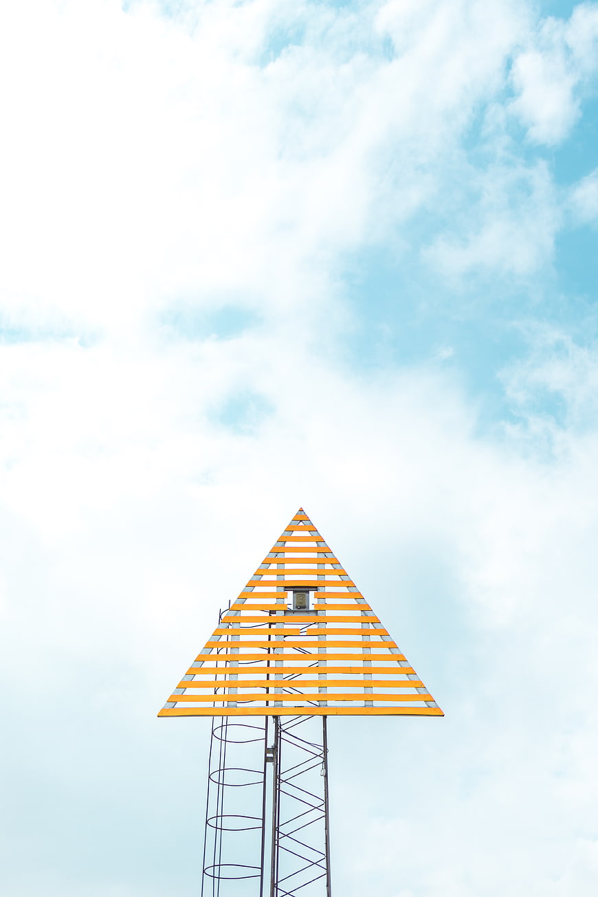 Yellow triangular tower structure against blue sky