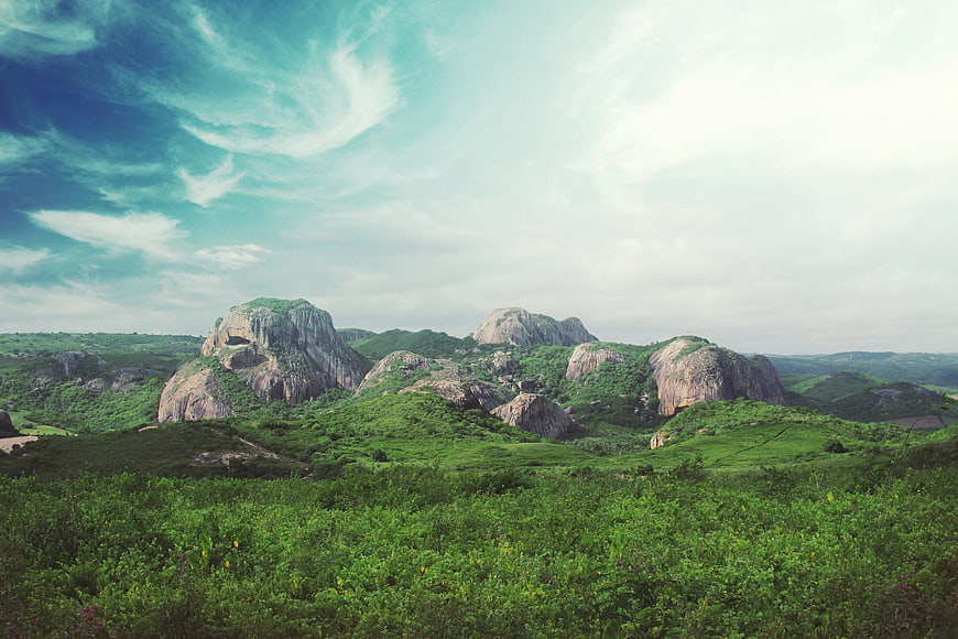 Lush Green Hills with Large Granite Boulders Under Blue Sky