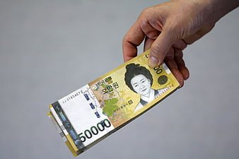 Hand holding a stack of South Korean 50,000 won banknotes