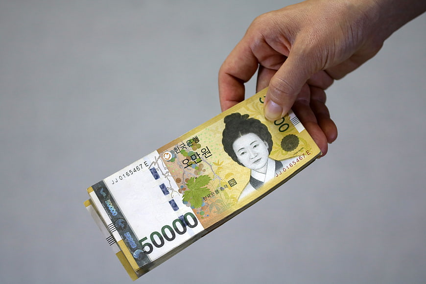 Hand holding a stack of South Korean 50,000 won banknotes
