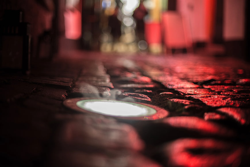Close-up of glowing LED light on wet wooden table with red reflections