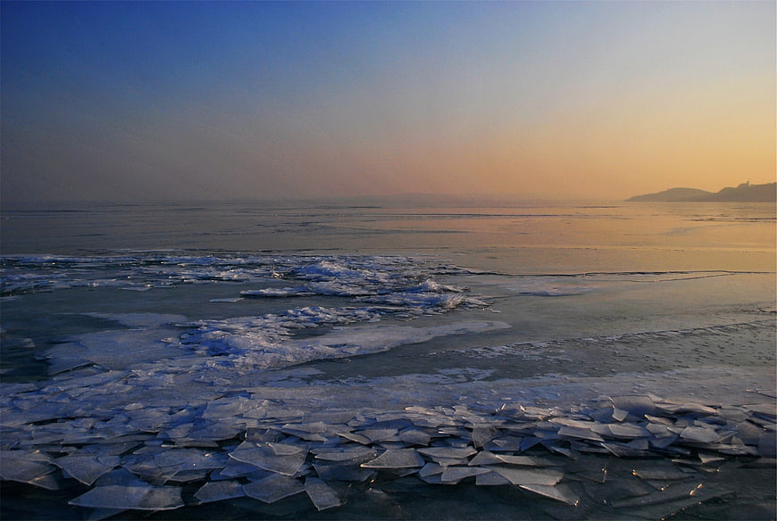 Frozen Lake Ice Shards at Sunset with Distant Mountains