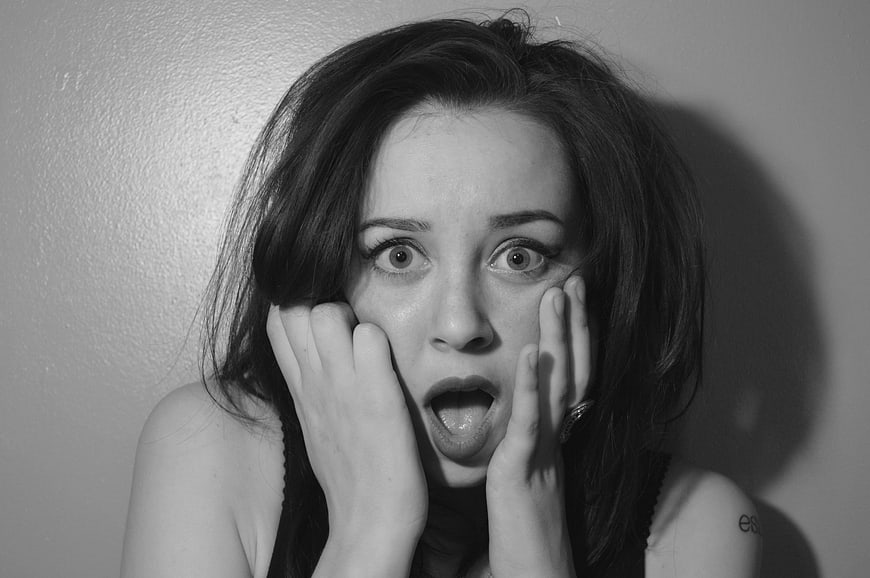 Black and white portrait of shocked woman with hands on face