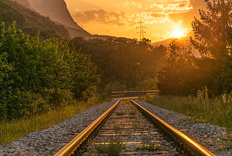 Golden sunset over winding railway tracks in mountain forest