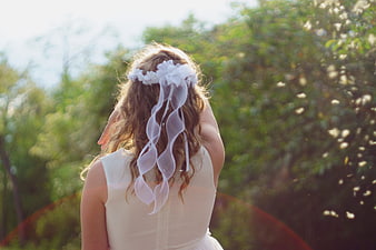 Girl in white communion dress with floral headpiece in garden