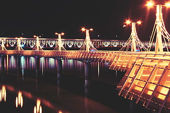 Illuminated modern bridge at night with water reflections