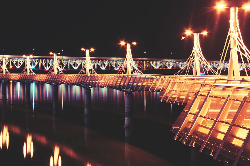 Illuminated modern bridge at night with water reflections