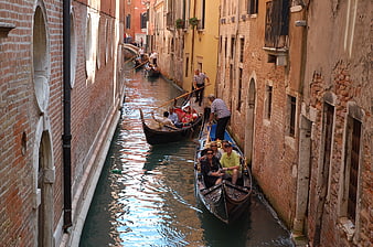 Gondolas navigating narrow Venetian canal between old brick buildings
