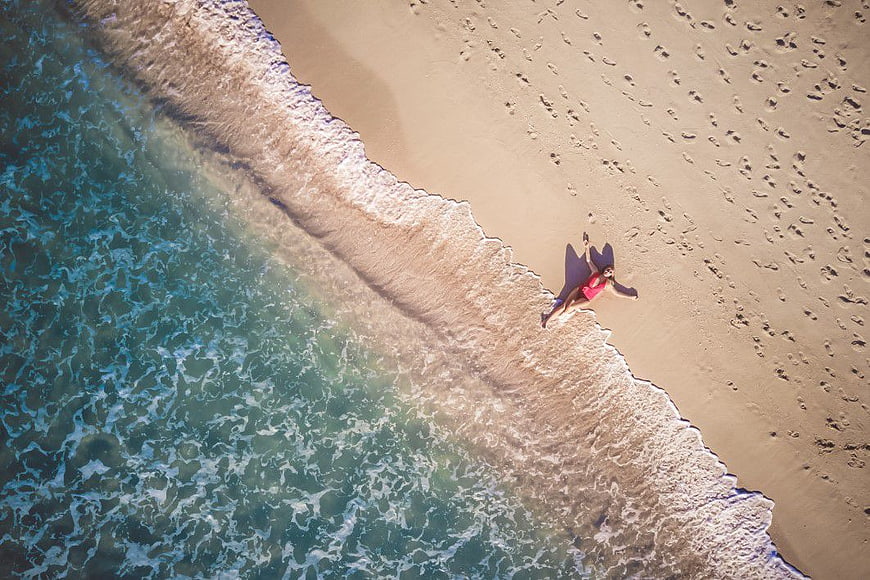 Aerial View of Woman in Red Swimsuit Lying on Sandy Beach