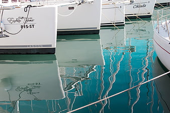 White yacht sterns with reflections in turquoise harbor water