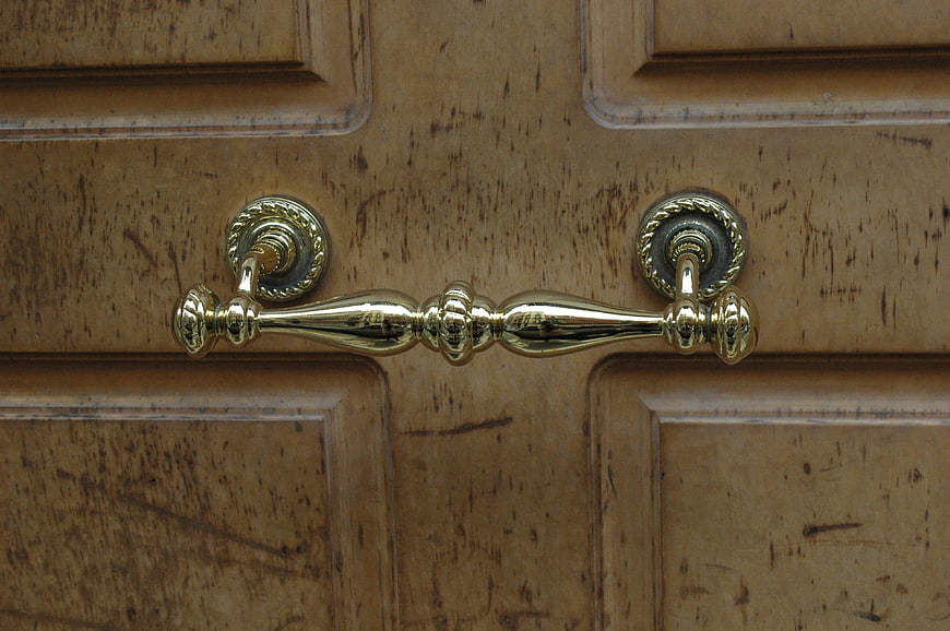 Close-up of vintage brass door handle on wooden door