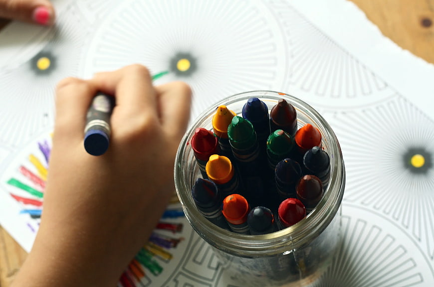 Child Coloring with Crayons on Mandala Pattern